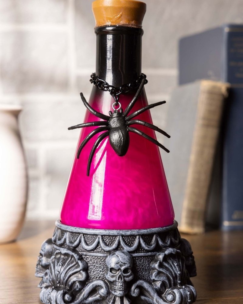 Light-up potion bottle Halloween decoration with glowing pink liquid and spider