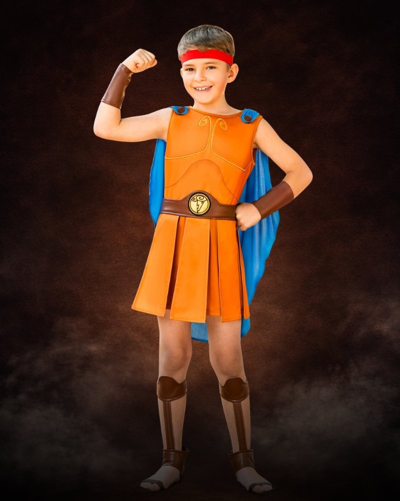 Boy wearing a premium Disney Hercules Halloween costume with orange tunic, blue cape, and heroic accessories