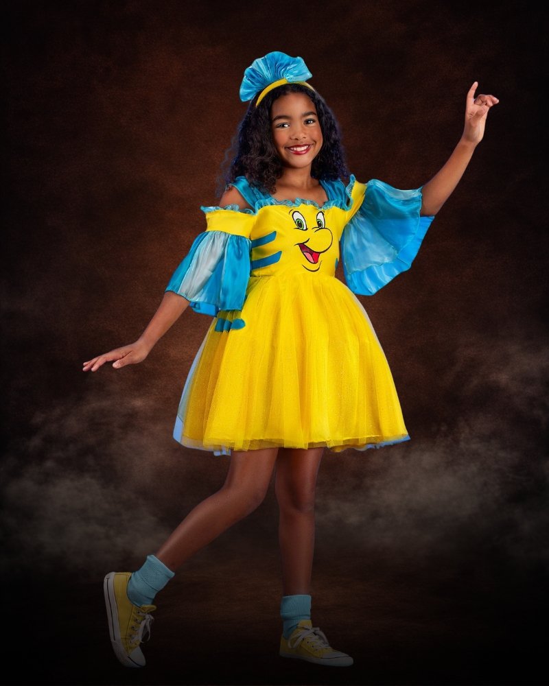 Girl wearing Disney Flounder costume dress with yellow satin skirt, blue fin ruffles, glitter tulle overlay, and matching headban