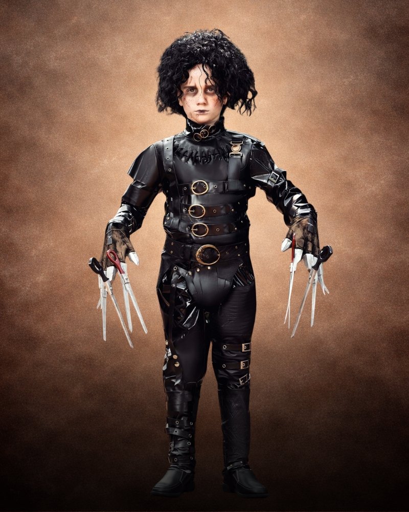Authentic Edward Scissorhands costume for boys with black leather-look outfit, buckles, straps, curly wig, and scissor blade gloves.