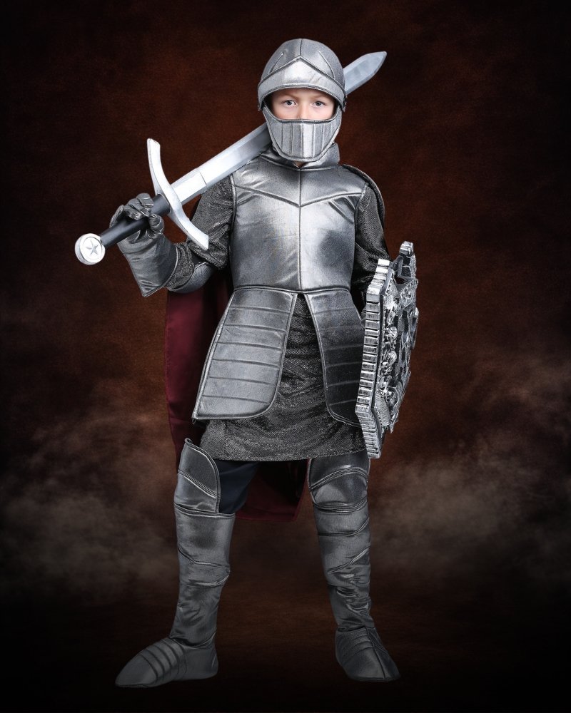 Royal Knight Costume for Boys with silver armor, medieval helmet, burgundy cape, gauntlets, and armored boot covers.